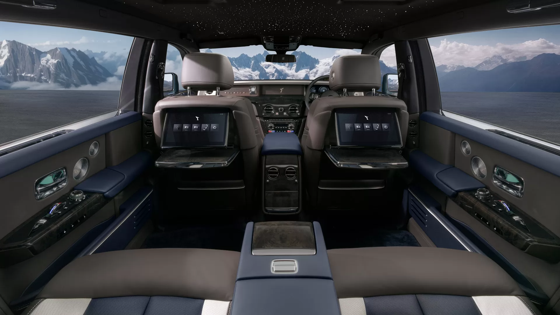 Interior view from the backseat perspective of the Rolls-Royce Phantom. Showcasing the brown leather and advanced interior. Outside of the front window is the mountain tops.