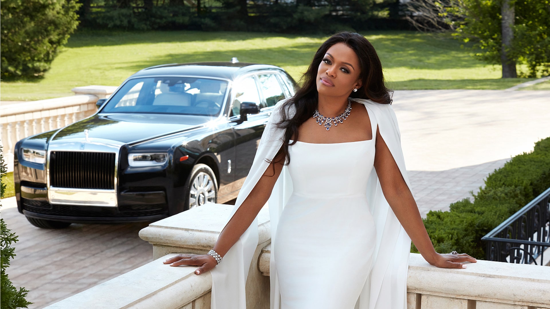 Ella Peters in a white dress in front of her Rolls-Royce Phantom