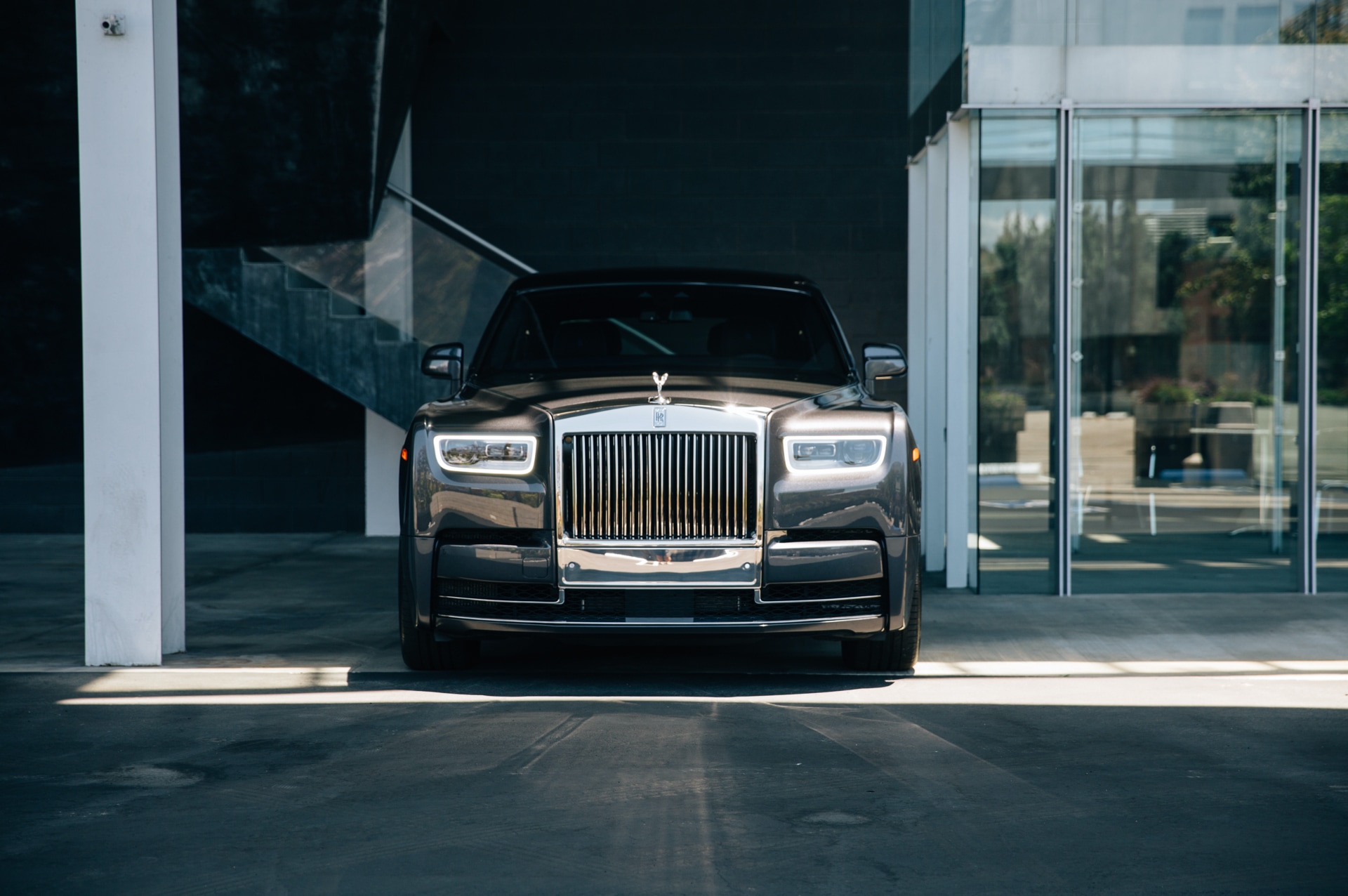 A front-on shot of the Rolls-Royce Phantom with bright sunlight reflecting against the Pantheon Grille and headlights