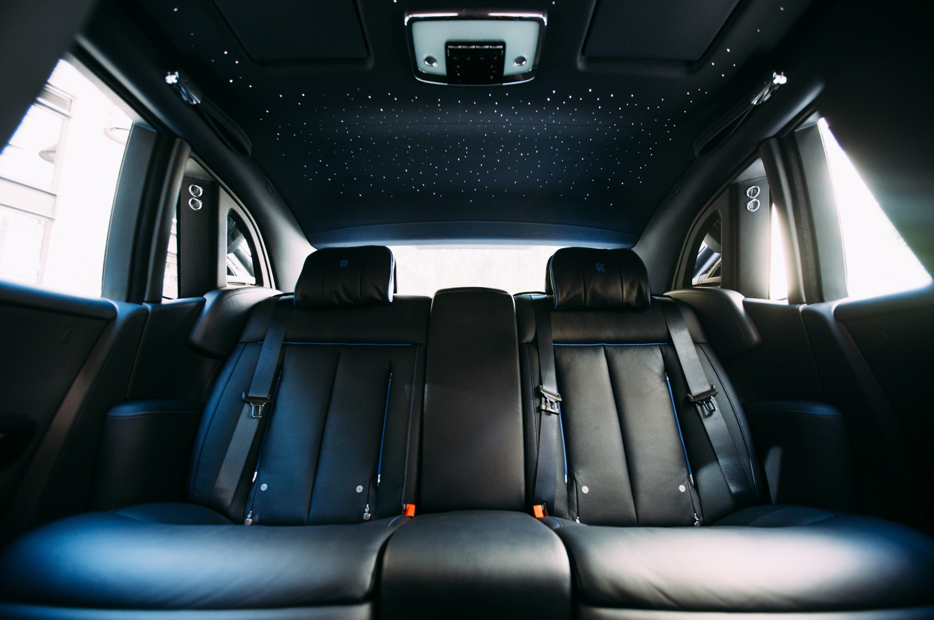 An interior rear shot of a Rolls-Royce Phantom showing the dark leather seats and starlight headliner accessory