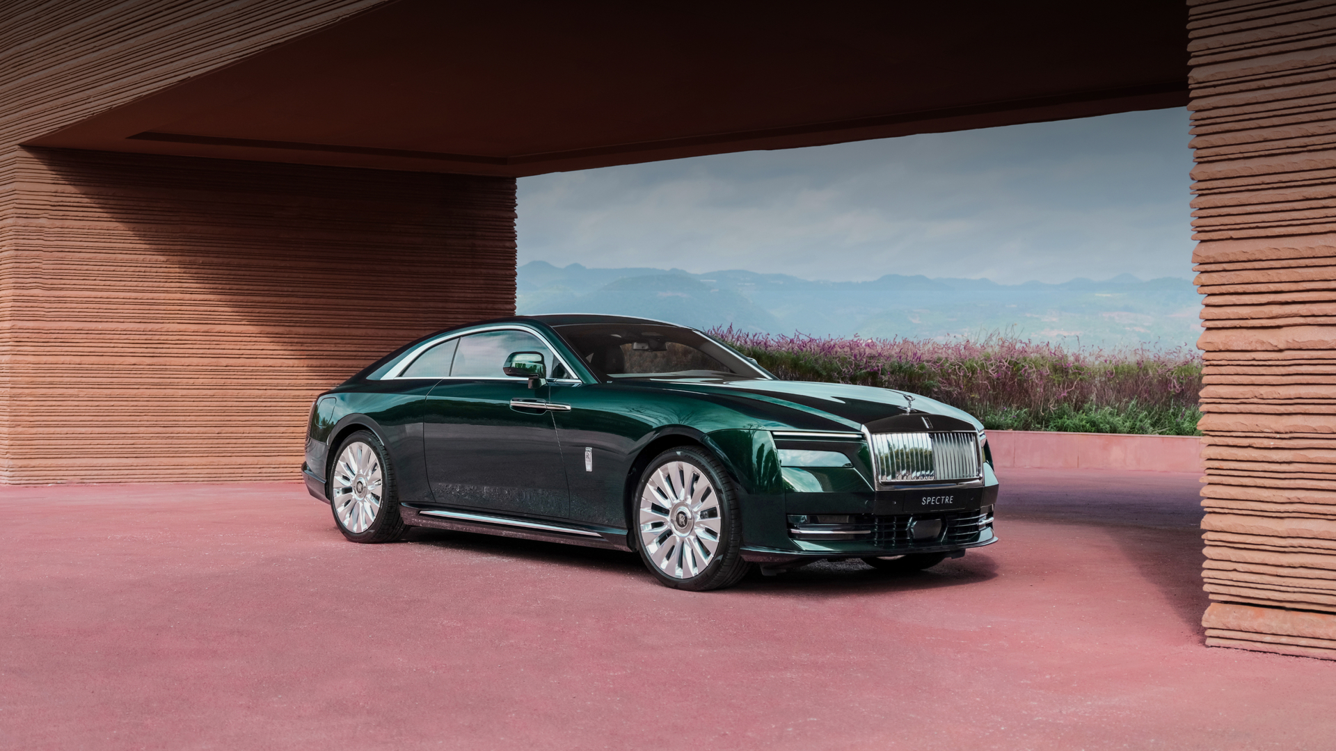 Front angled shot of a Green Spectre sitting infront of a pink flower garden.