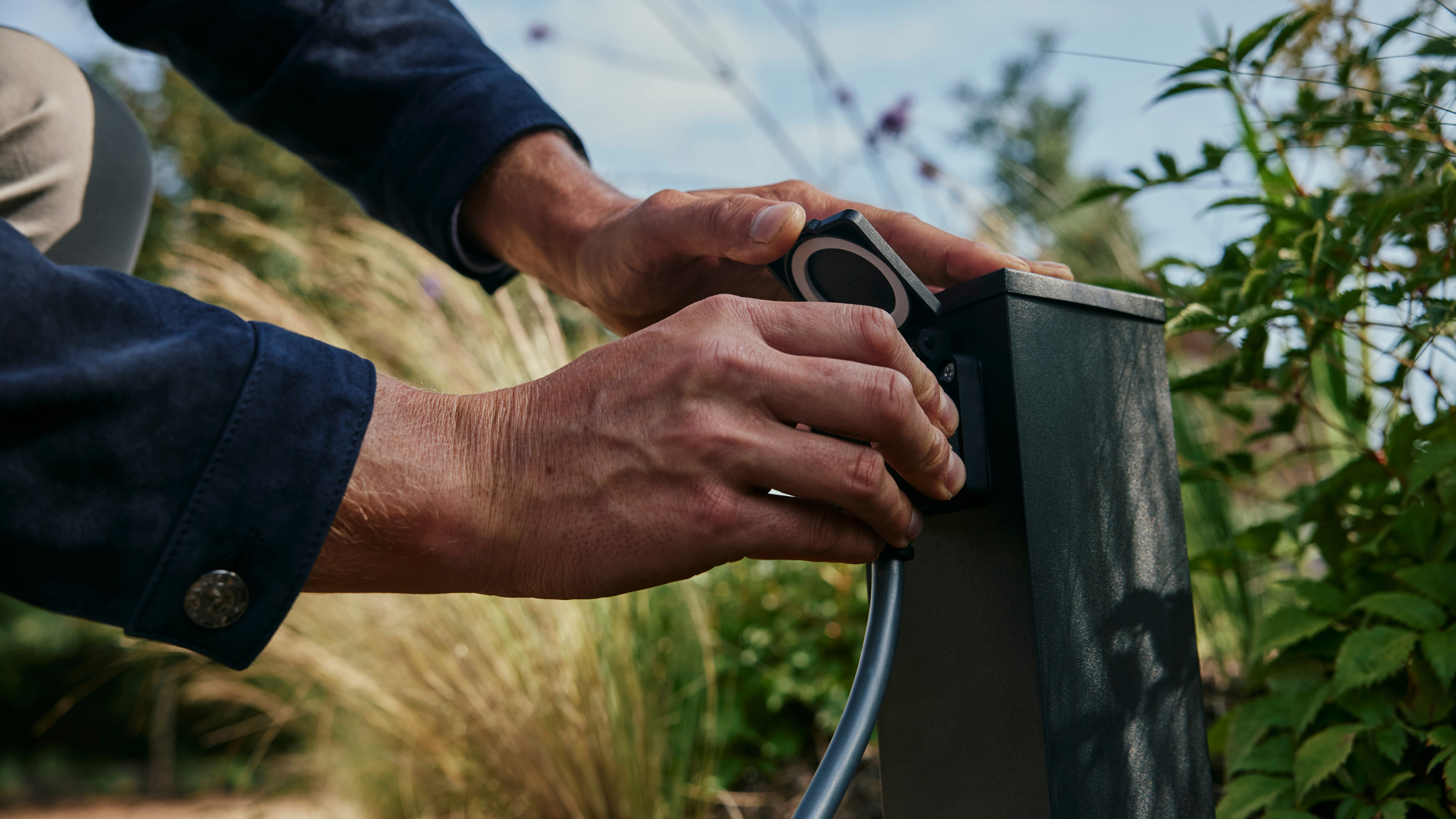 A hand of a man plugging in a charging cable to charge his Spectre