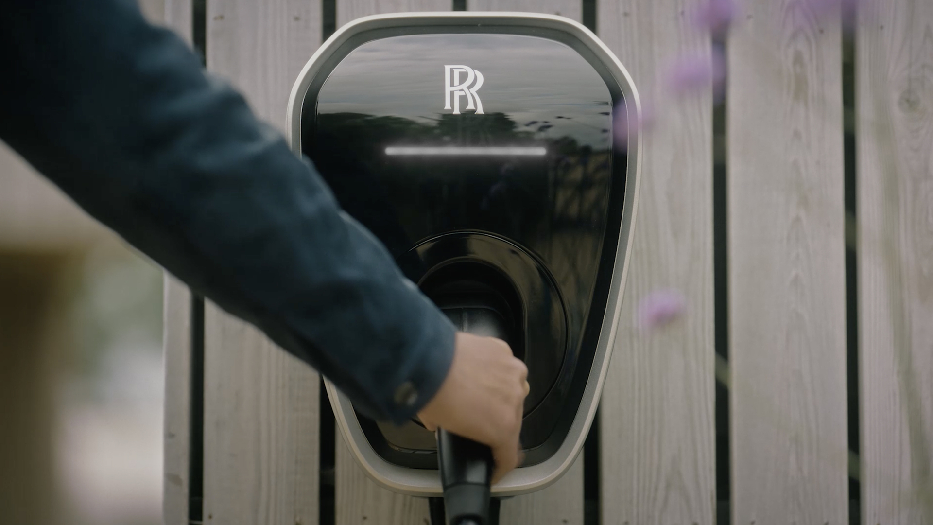 A man pulling the the charging cable out of a private charging station to charge his Spectre