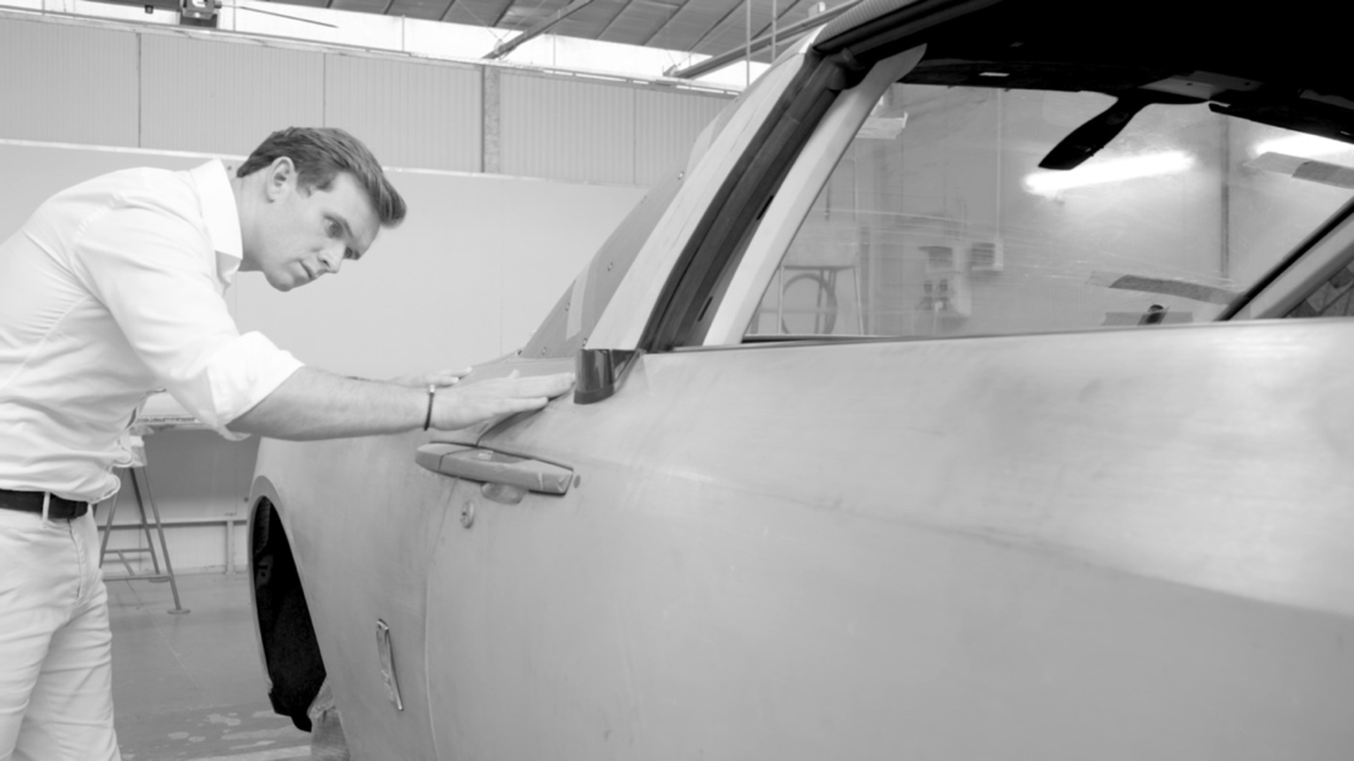 black and white image of man reviewing the detail of the car